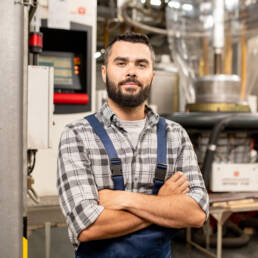 Hombre en planta industrial de pl&aacute;sticos y pol&iacute;meros, con uniforme de trabajo.
